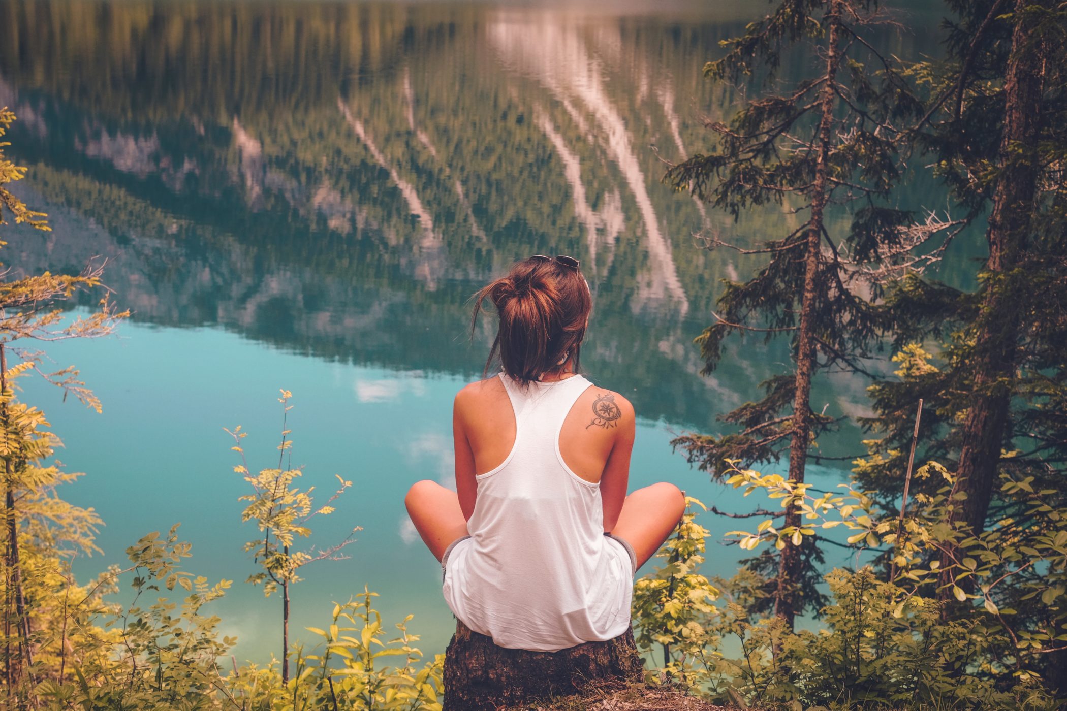 Must Have Items for a High Vibe Summer - Woman Meditating in Serene Forest