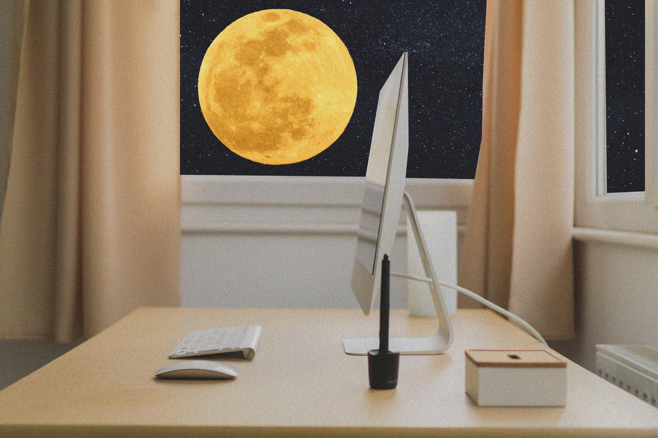 Desk with windows open showing the night sky with yellow full moon in background.