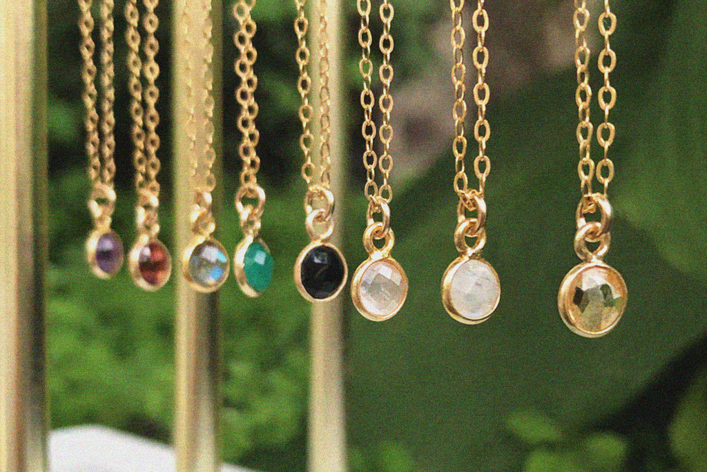 Multiple gold necklaces hanging with muti coloured crystals