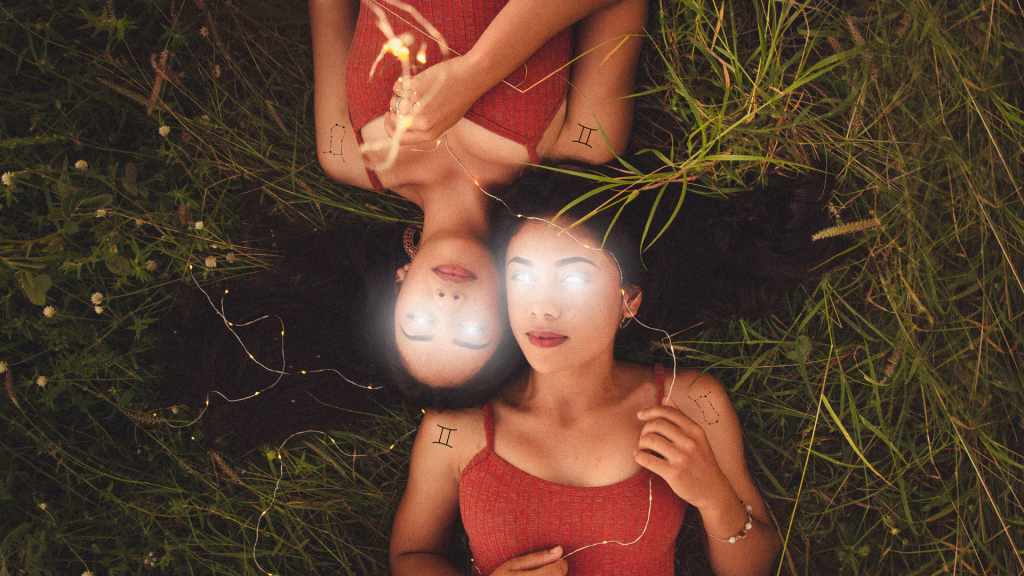 Twins laying down in grass with light beams coming from their eyes and Gemini tattoos.